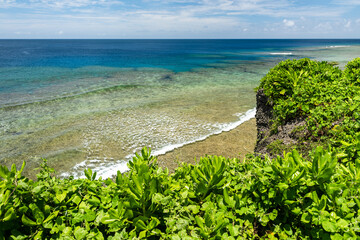 Sea rising and small waves passing over the coral platform. Cliff full of vegetation around, horizon with stunning turquoise sea. Scene seen from a cliff. Iriomote Island.