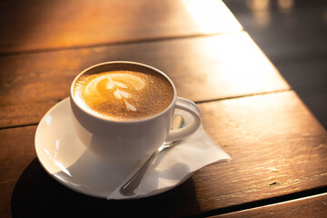 A cup of hot coffee on wooden table. Beverage in the afternoon. Latte coffee design.