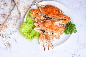 Fresh seafood crab on white plate cooking food in the restaurant, Steamed or boiled Blue Swimming Crab ocean gourmet with salad vegetables lettuce, top view