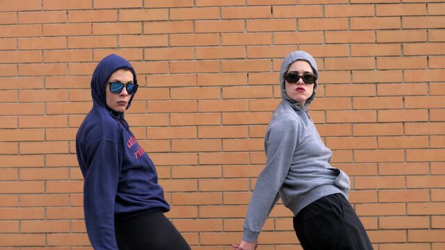 synchronism, timing - hooded girls dance in hip hop style looking at camera