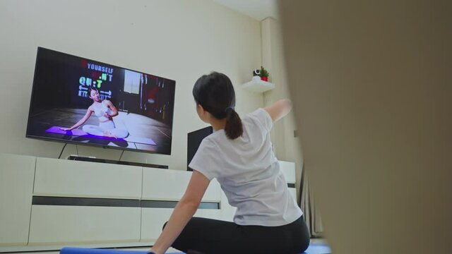 Asian girl learning yoga online to exercise from video tutorial.