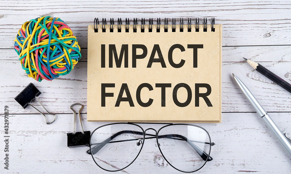 Poster notebook with text impact factor and office supplies. view from above. closeup on white background