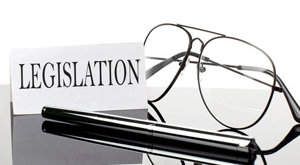 Text LEGISLATION on paper on light background with pen and glasses. Business concept