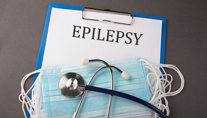 Folder with paper text EPILEPSY , on a table with a stethoscope and medical masks, medical concept.