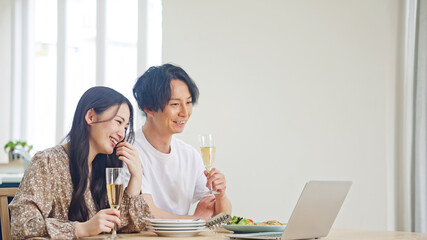 食事をしながらパソコンを見るカップル　オンライン飲み会　動画鑑賞