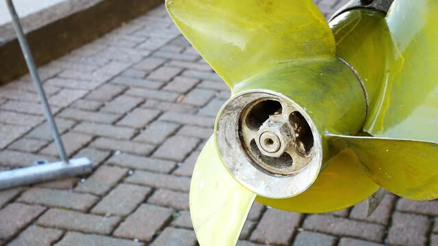 Yellow metal yacht boat propeller rotor blades under maintenance vessel in shipyard closeup dolly right