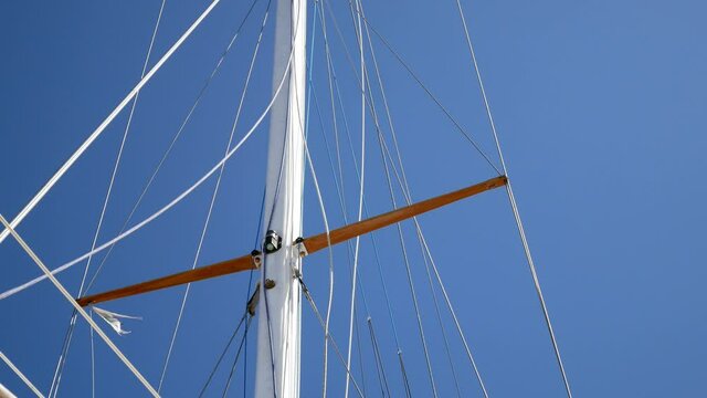 Sailing ship mast rigging rope blowing in wind against blue sky low angle closeup