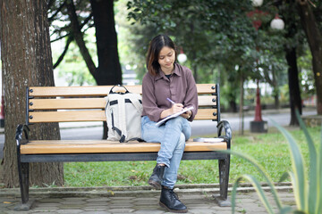 Naklejka na ściany i meble Young woman studying at the park.