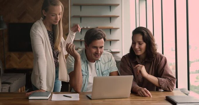 Young and ambitious team of office employees creative workgroup working together on project look at laptop discuss task, share ideas and thoughts. Well-planned teamwork, workflow, cooperation concept