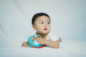 Fototapeta na wymiar asian baby girl in 6 month with toy on floor fabric with white background for learning and development concept