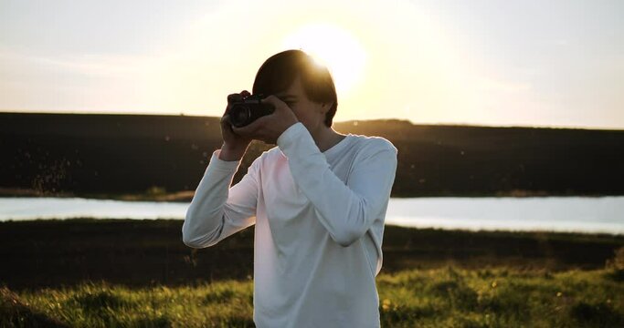 Man of young appearance, photographing, looking for a good angle for a shot.