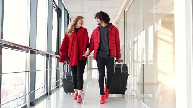 Couple in red clothing with suitcases going for flight