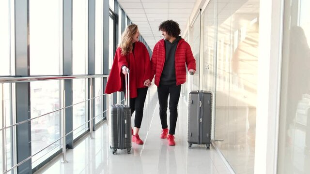 Couple in red clothing with suitcases going for flight