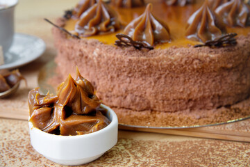 Sweet chocolate cream in a bowl on the background of the cake.