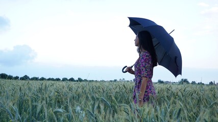 side woman holding an umbrella in a wheat field
