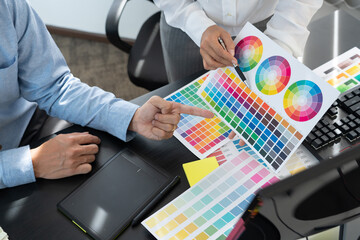 Graphic designer or creative working together coloring using graphics tablet and a stylus at desk...