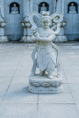 Stone carved statue of Buddhist guardian at local temple.