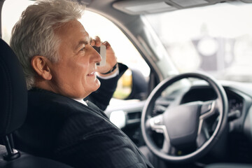 Senior businessman talking by mobile phone in modern car