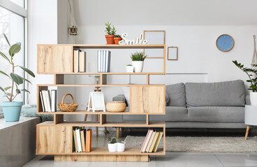 Shelf unit with books and sofa in interior of room