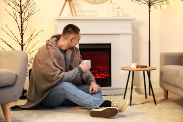 Handsome man with cup of tea looking at fireplace