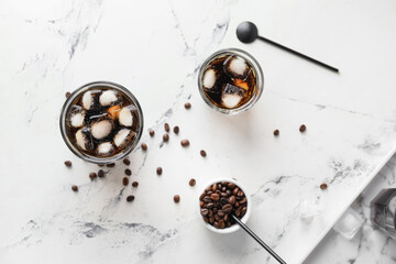 Glasses of tasty cold brew and coffee beans on light background
