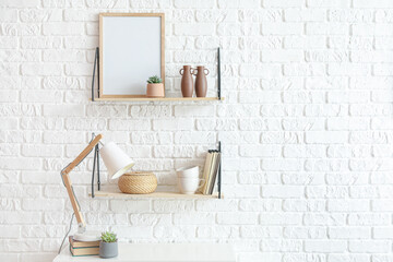 Modern shelves with decor and lamp near brick wall
