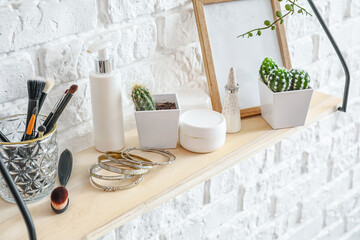 Shelf with makeup brushes and decor hanging on brick wall