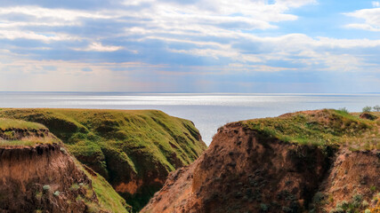 Landscape view clay cape mountains and cliffs near blue sea and skyline. Seascape of coast from green meadows. Clay rock in front of sea. Sea view horizon. Secluded nature tourism. Long web banner