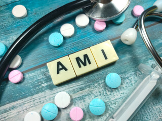 Text AMI (Acute myocardial infarction) on a table with a stethoscope,syringe and pills. Medical concept.