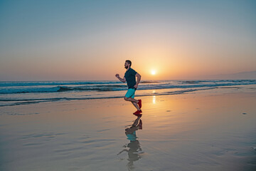 Active healthy runner jogging outdoor. Young and active jogger running on beach sunset.