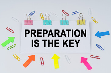 On the table there are paper clips and directional arrows, a sign that says - PREPARATION IS THE KEY
