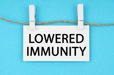 On a blue background, a white plaque hangs on a rope with the inscription - LOWERED IMMUNITY