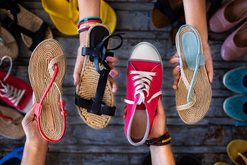 Shoes at the hands of two women, canvas shoes . flip flops and sandals