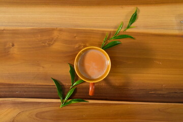 Wooden background, tea in cup with leaves.