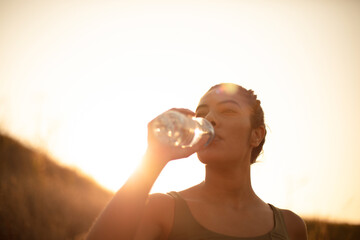 Sporty young woman drinking water outdoors. Time for refresh.