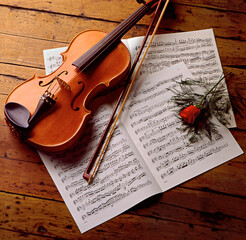 Naklejka premium Violin with sheet music and a red rose.