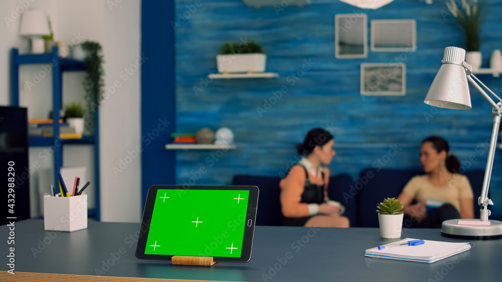 Poster tablet computer with mock up green screen chroma key display standing in front on office desk. two c
