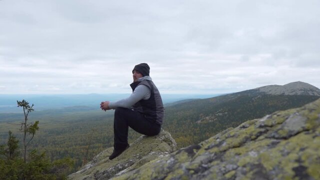 A Man At The Top Of A Cliff And Enjoying A Mountain Landscape, Relaxes And Gains Calm. The concept of Solitude and Love for Nature