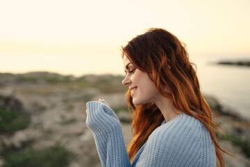 cheerful woman in a blue sweater outdoors sunset travel vacation