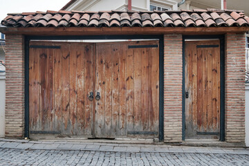 Old wooden gate with a large round metal handles and tiled roof