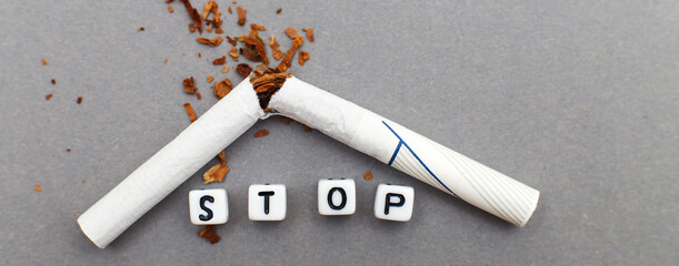 broken cigarette with the word stop on gray background close. stop smoking concept. banner