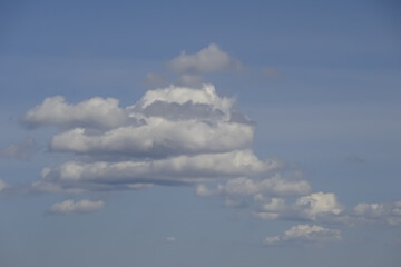 Skyscape of light blue sky and white fluffy clouds background during daytime