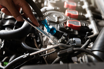 Obraz premium Auto mechanic man with wrench repair and maintenance to customer the engine a vehicle car hood in auto mechanics garage.