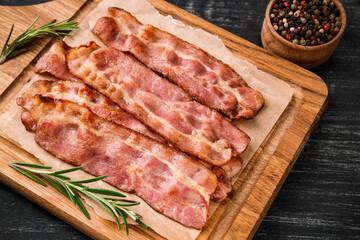 Hot fried bacon with rosemary on a black background.