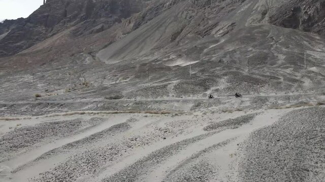 Aerial drone side view footage of two bikers riding through the mountain road of Ladakh. Road trip in Ladakh in motor bikes.