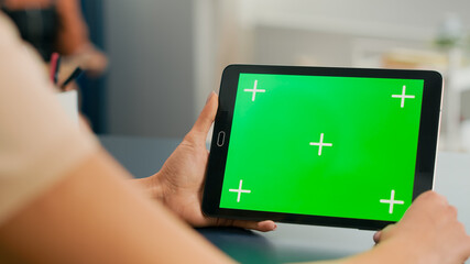 Tablet computer with mock up green screen chroma key display standing on table desk. Freelancer...