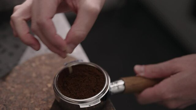 Closeup of man spreading and tamping fresh coffee in pottomless portafilter