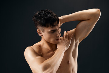 sporty man with pumped up muscular body holds his hand behind his head posing