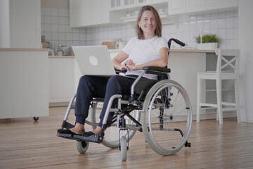 Portrait of beautiful young caucasian paralyzed woman in wheelchair sitting in living room, smiling and looking at camera