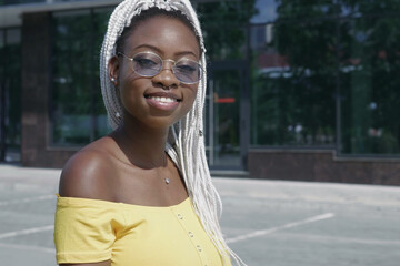 Portrait of a cheerful beautiful African American woman wearing sunglasses posing outdoors by...